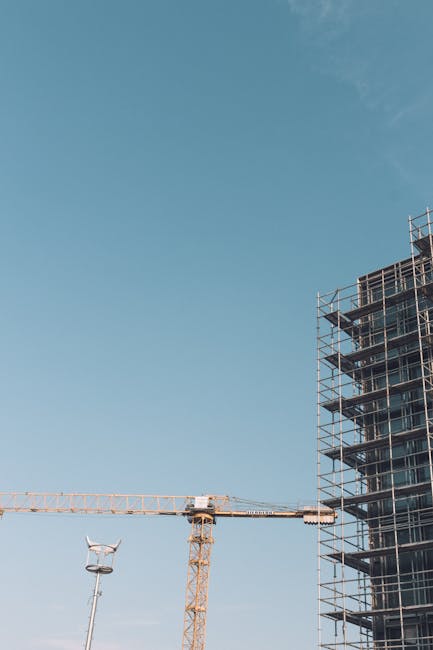 High-rise building construction with crane under a clear blue sky, showcasing urban development.