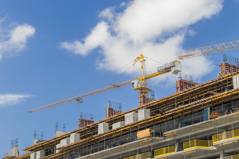 A modern construction site with cranes against a clear blue sky, showcasing urban development.