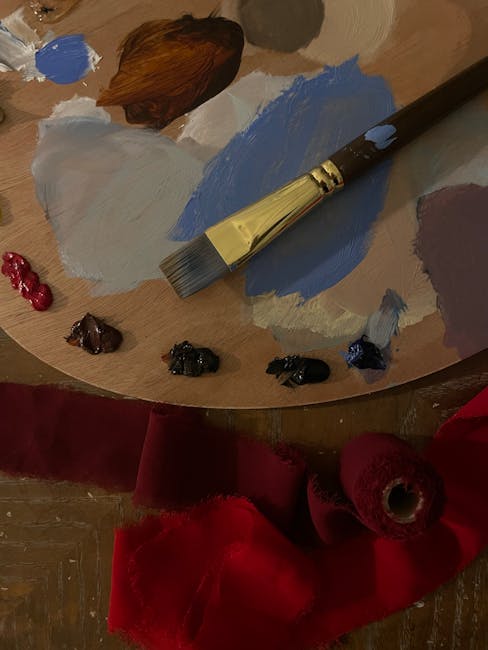 Close-up of an artist's palette with mixed paints and a brush on wood surface.