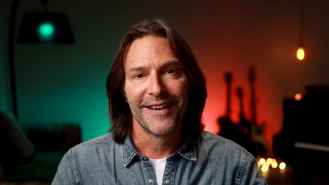 Eric Whitacre smiling close-up with colorful studio lighting