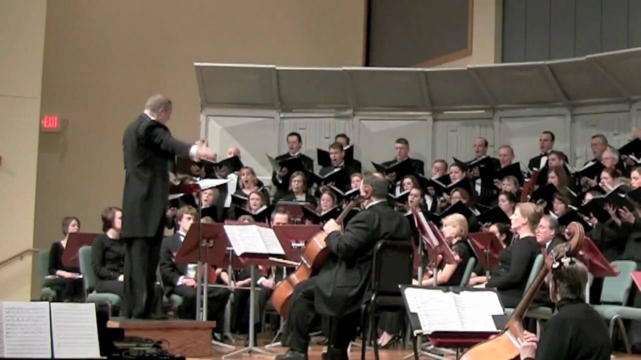 Choir performing with conductor and cellos visible