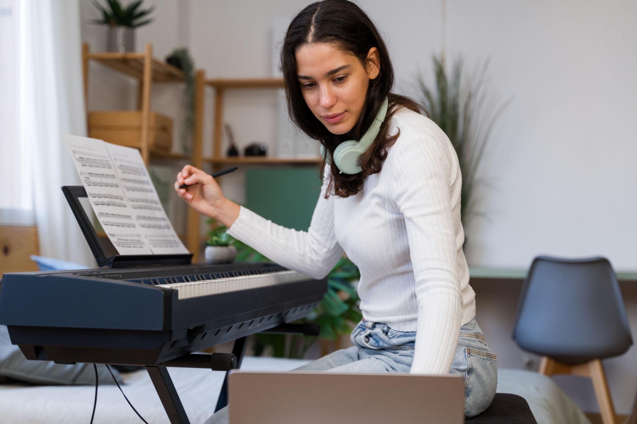 Musician composing music using a laptop and a keyboard at home