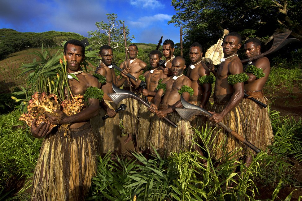 A group posing in a ginger field, with harvested ginger held in the foreground.