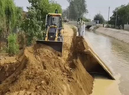 भोडियाखेड़ा में टूटी सिरसा ब्रांच नहर को ठीक करने में जुटा जेसीबी चालक।
