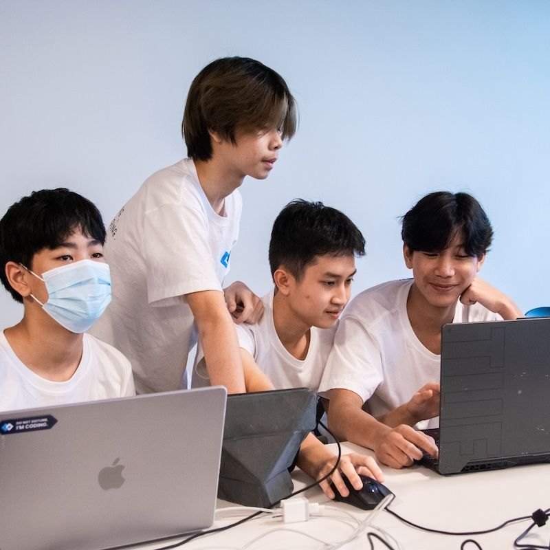 นักเรียนสี่คนกำลังร่วมกันทำการบ้านหน้าแล็ปท๊อป