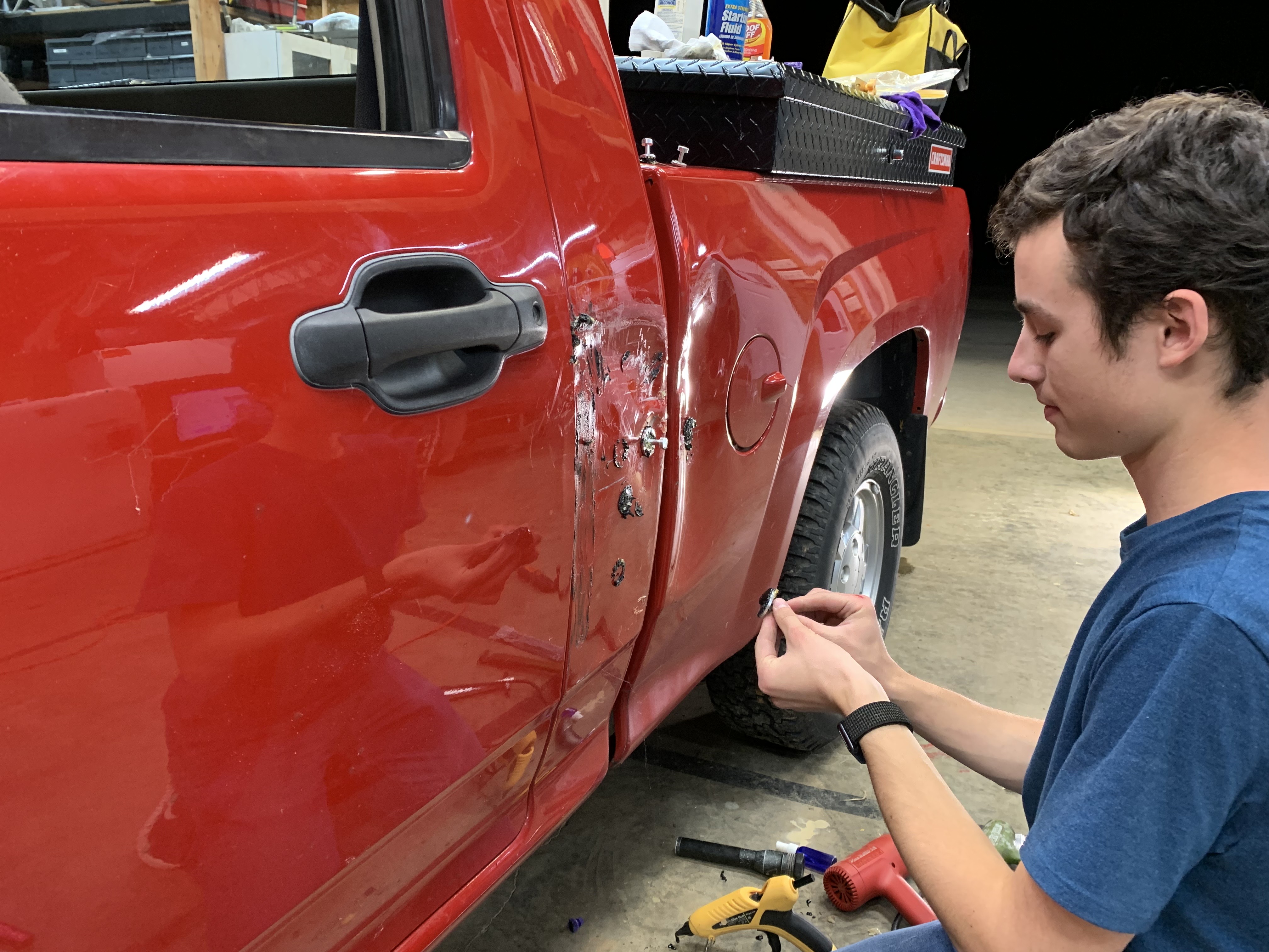 Luke working on pulling a dent out of his truck