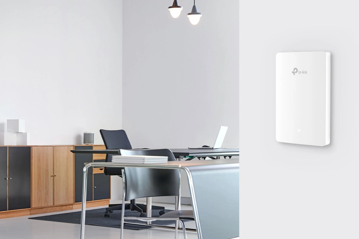 Modern office with sleek, minimalist design. Features a TP-Link router on a light wall, a wooden cabinet, metallic desk with chairs, and soft lighting.