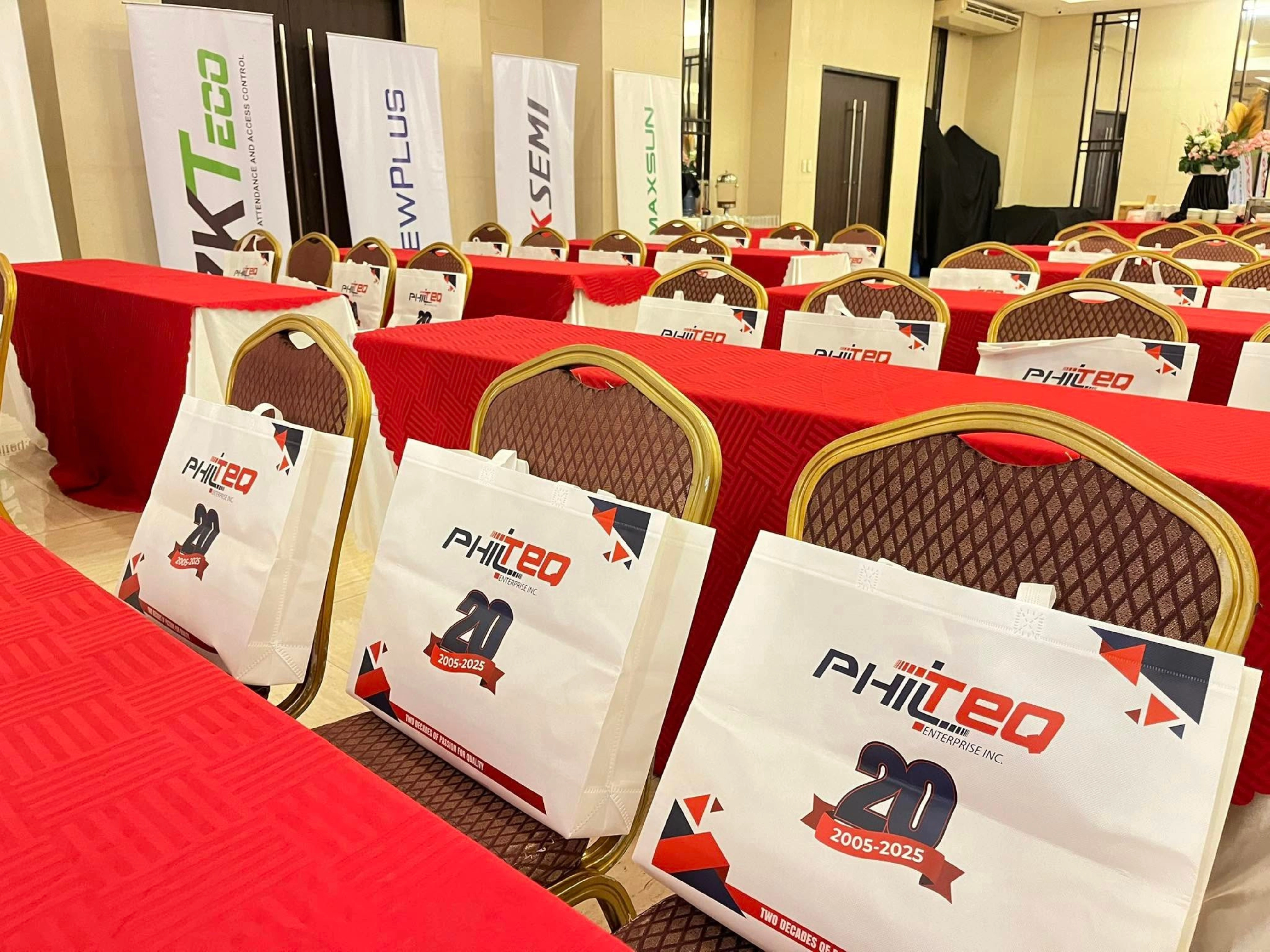 Chairs and tables set up for a corporate event, showing Philteo 20th anniversary bags and banners for ZKTeco, Viewplus, and Hiksemi.