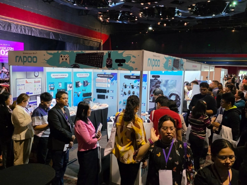 A crowded technology expo where visitors are gathered around the Rapoo booth showcasing computer peripherals and accessories.