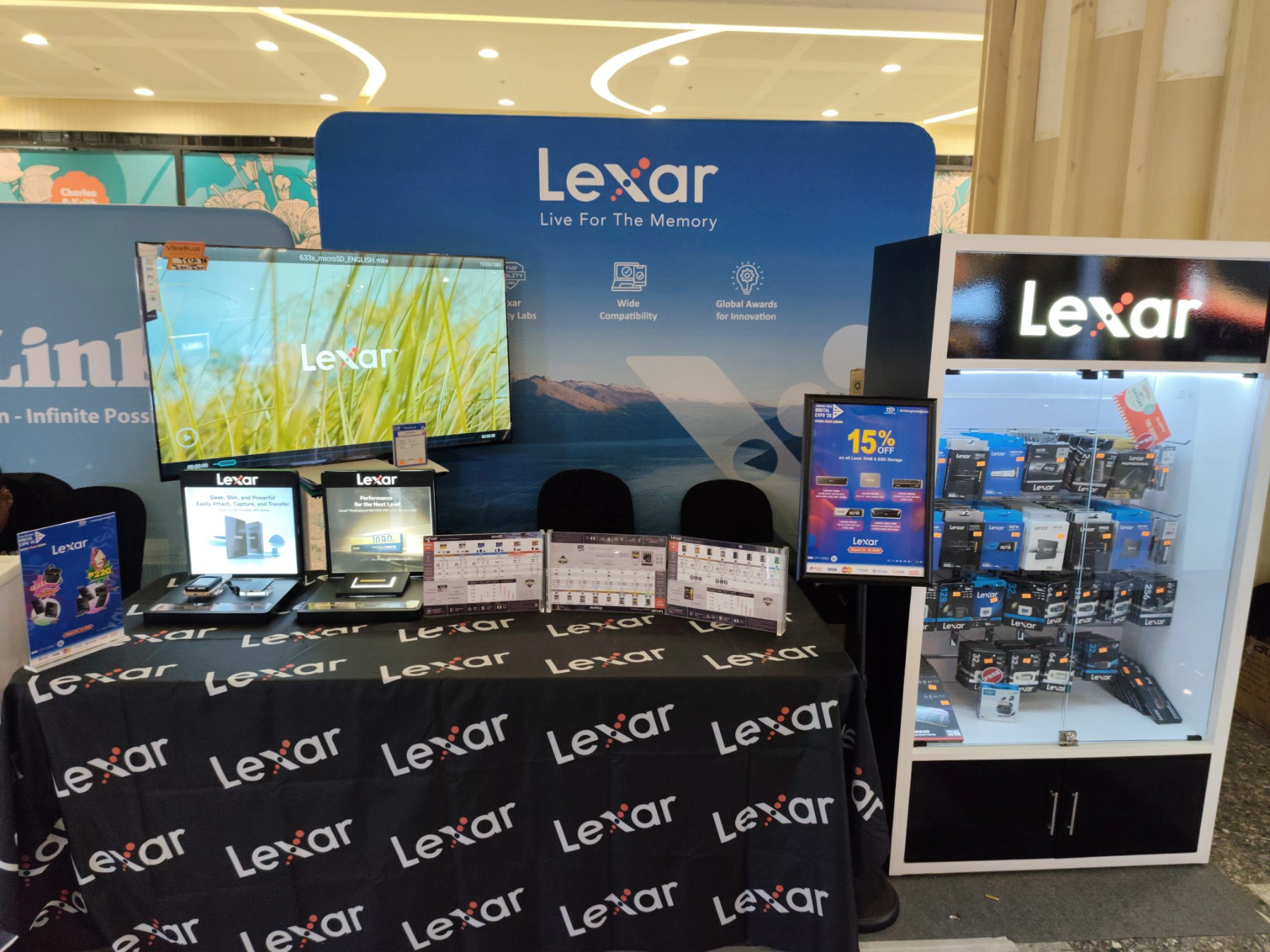 Lexar retail booth display at a store, featuring product showcases, monitors, and signs highlighting wide compatibility and global awards for innovation.