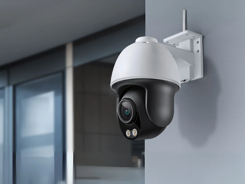 Surveillance camera mounted on a modern building wall, featuring a sleek black and white design. It conveys a sense of security and monitoring.