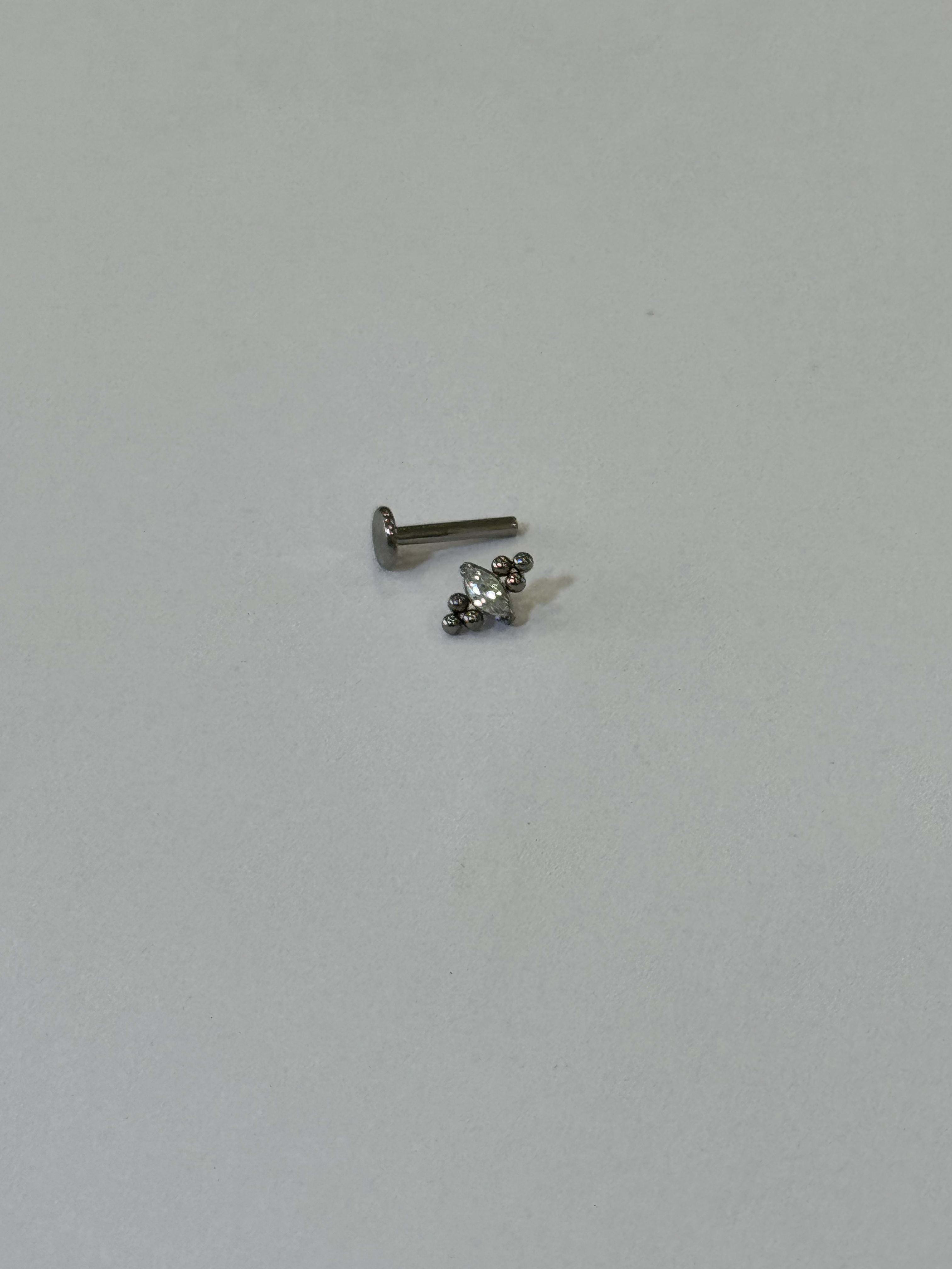 Piercing labret titanio 16G, zirconia ovalo al centro y balines mini