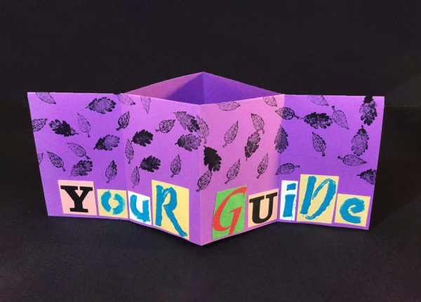 A purple zine with stamped images of leaves, halfway folded to reveal the words "Your Guide" in cutout letters.
