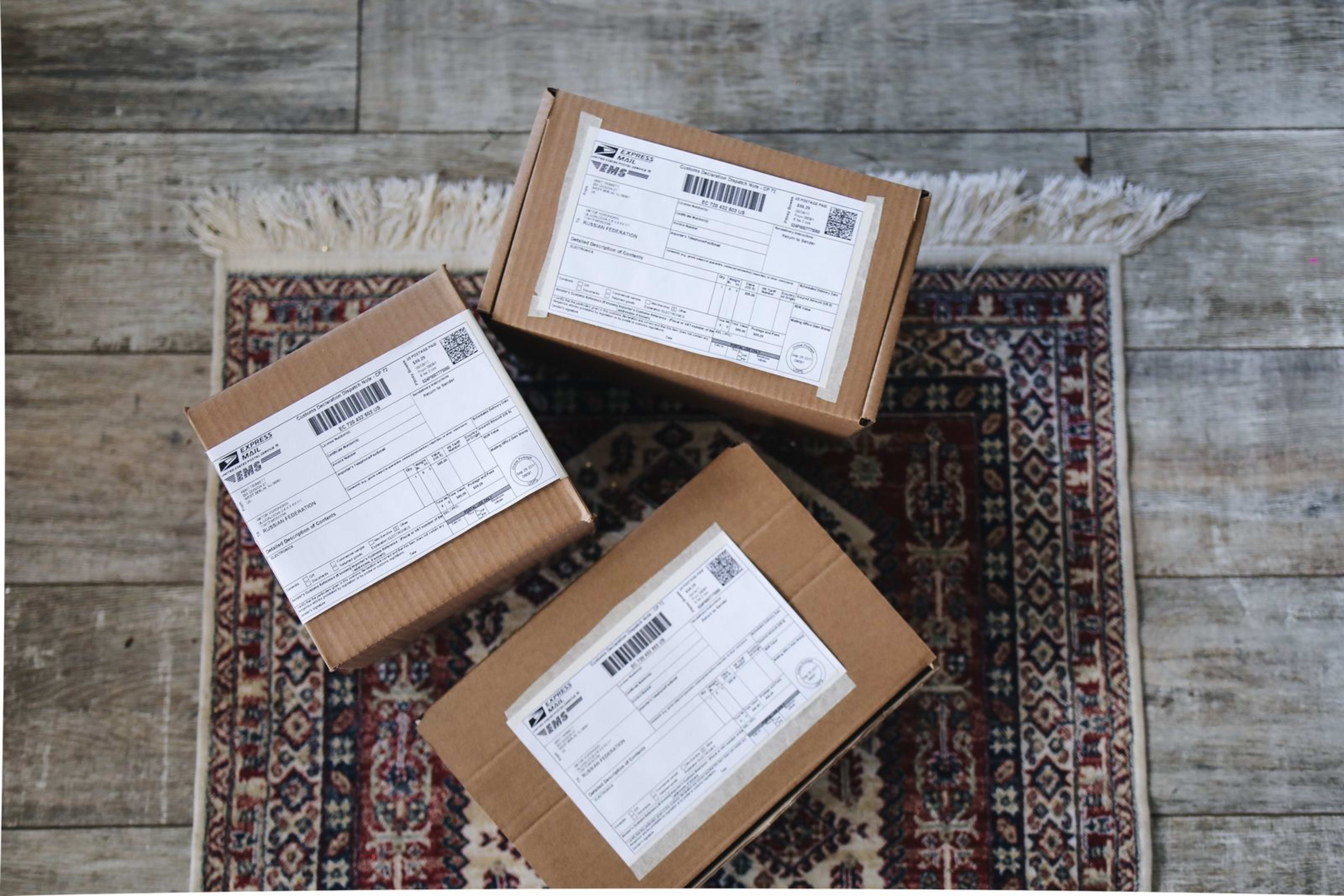 Three labeled express delivery boxes sitting on a decorative rug over a wooden floor.