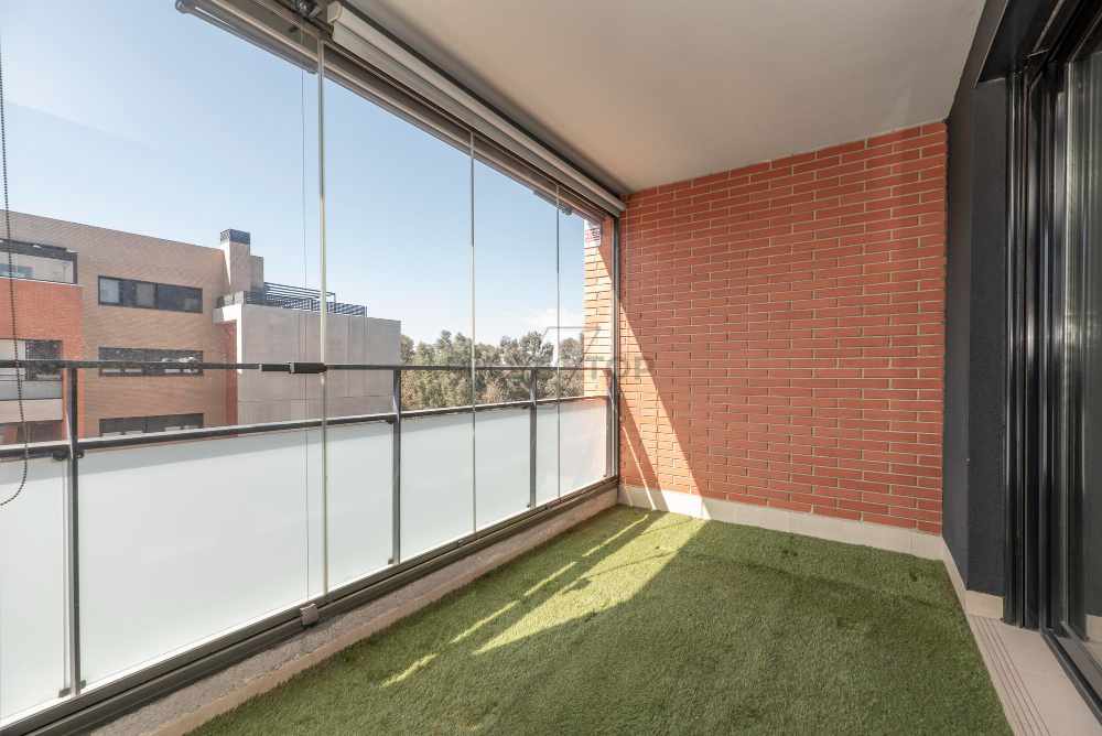 Terraza acristalada con pared de ladrillo con suelo de césped artificial y vistas a la ciudad