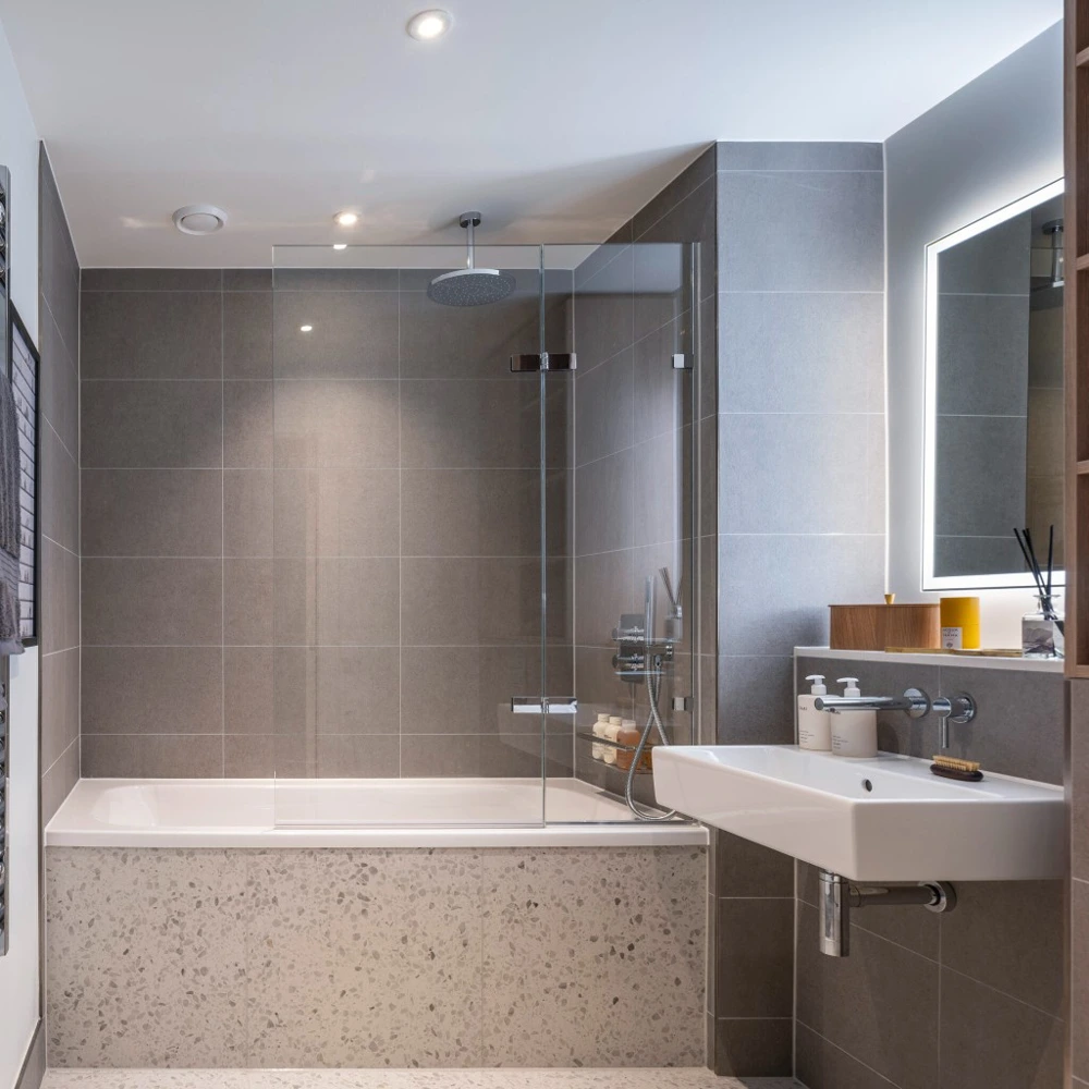 Thumbnail Modern bathroom at bloom nine elms with grey tiles, glass shower screen, and illuminated mirror over white sink