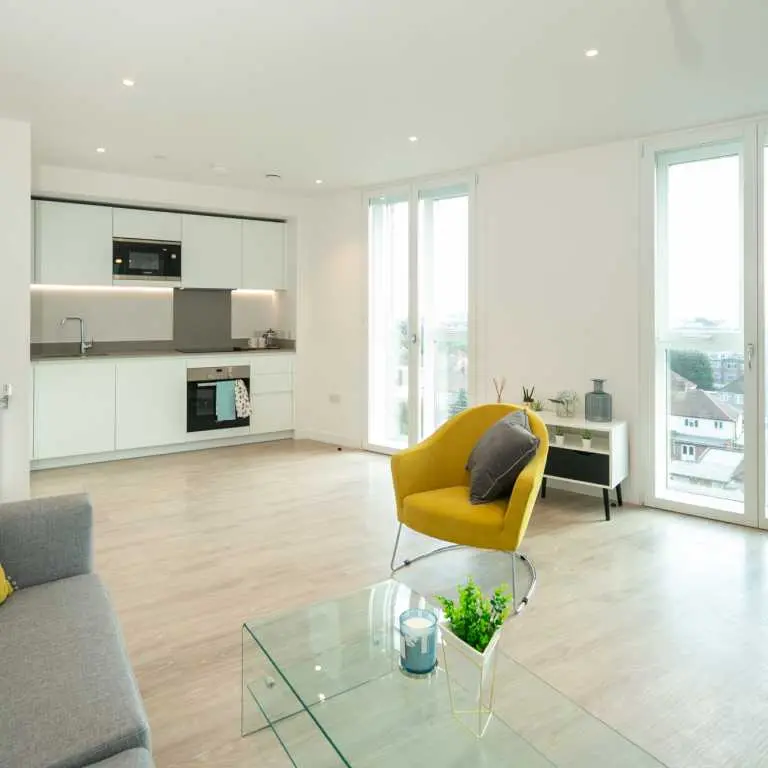 Thumbnail Open-plan kitchen and living area at Fizzy Hayes with modern white cabinetry and yellow accent chair
