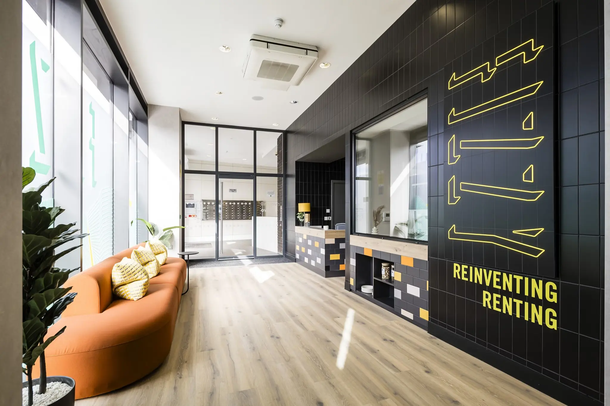 Thumbnail Modern lobby at Fizzy Lewisham with curved orange sofa, black tiled walls, and branding that reads Reinventing Renting