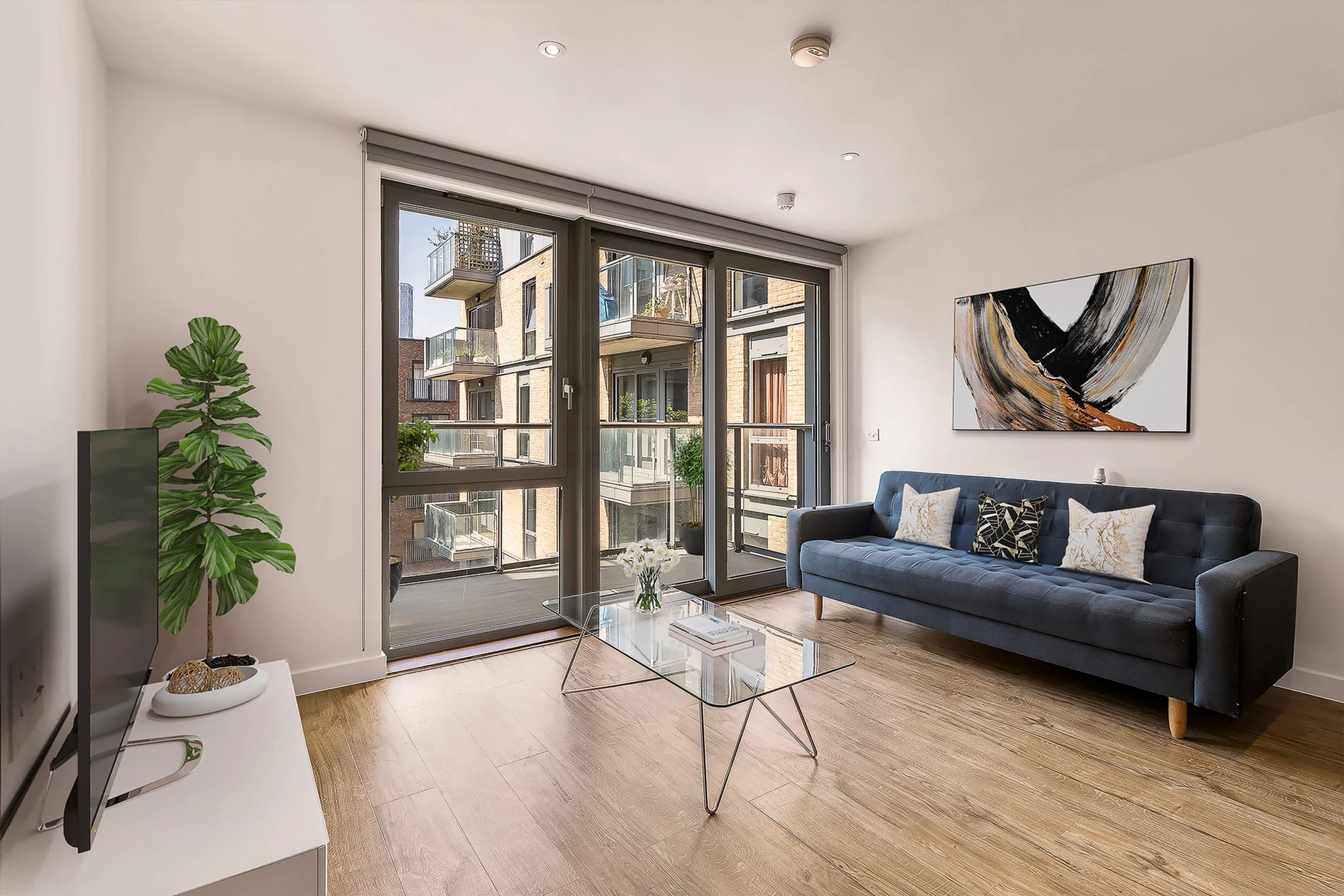 Thumbnail Modern living room at Fizzy Poplar with navy sofa, glass coffee table, and large windows opening to balcony views