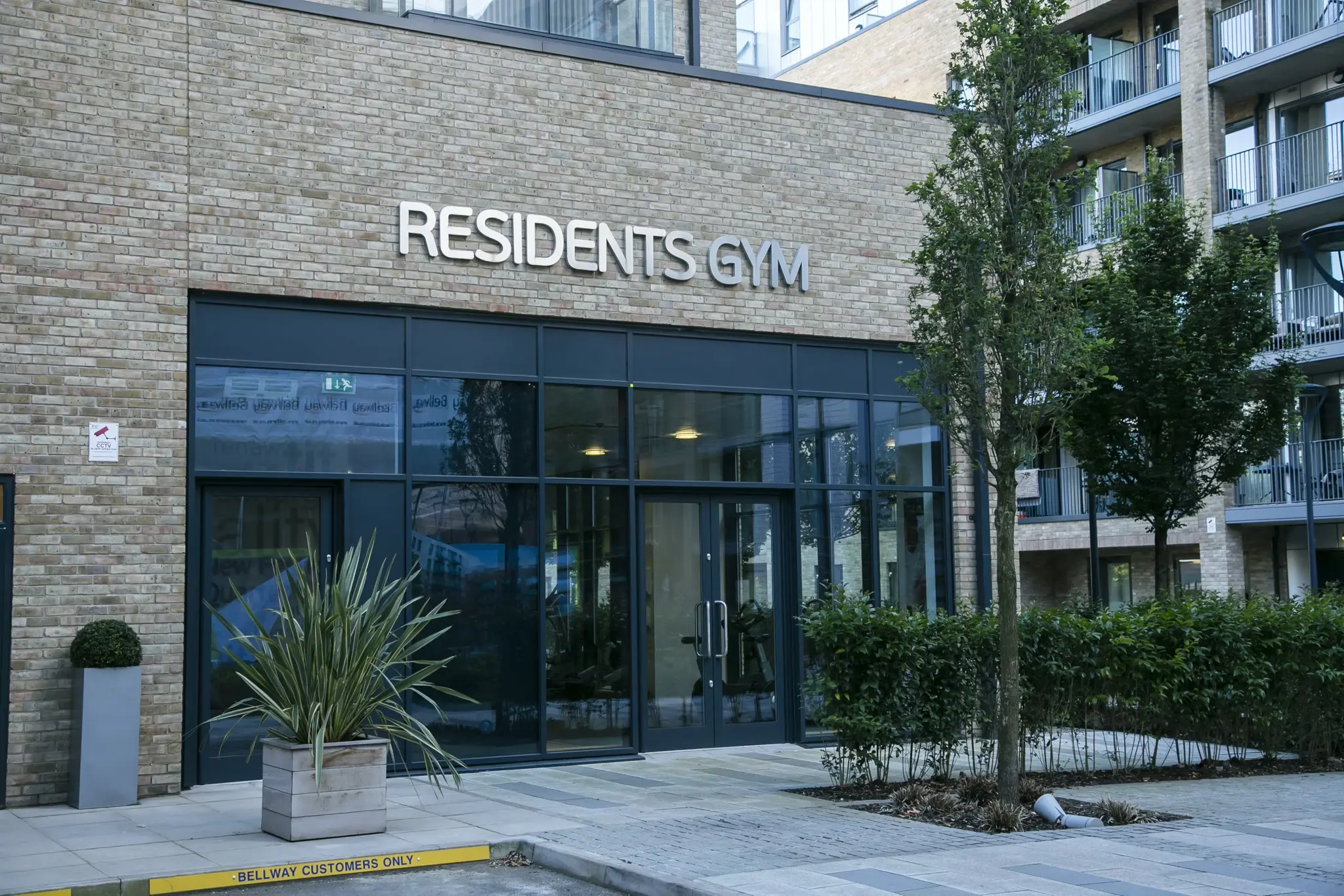 Thumbnail Exterior of the residents' gym at Fizzy Poplar with glass entrance and surrounding greenery