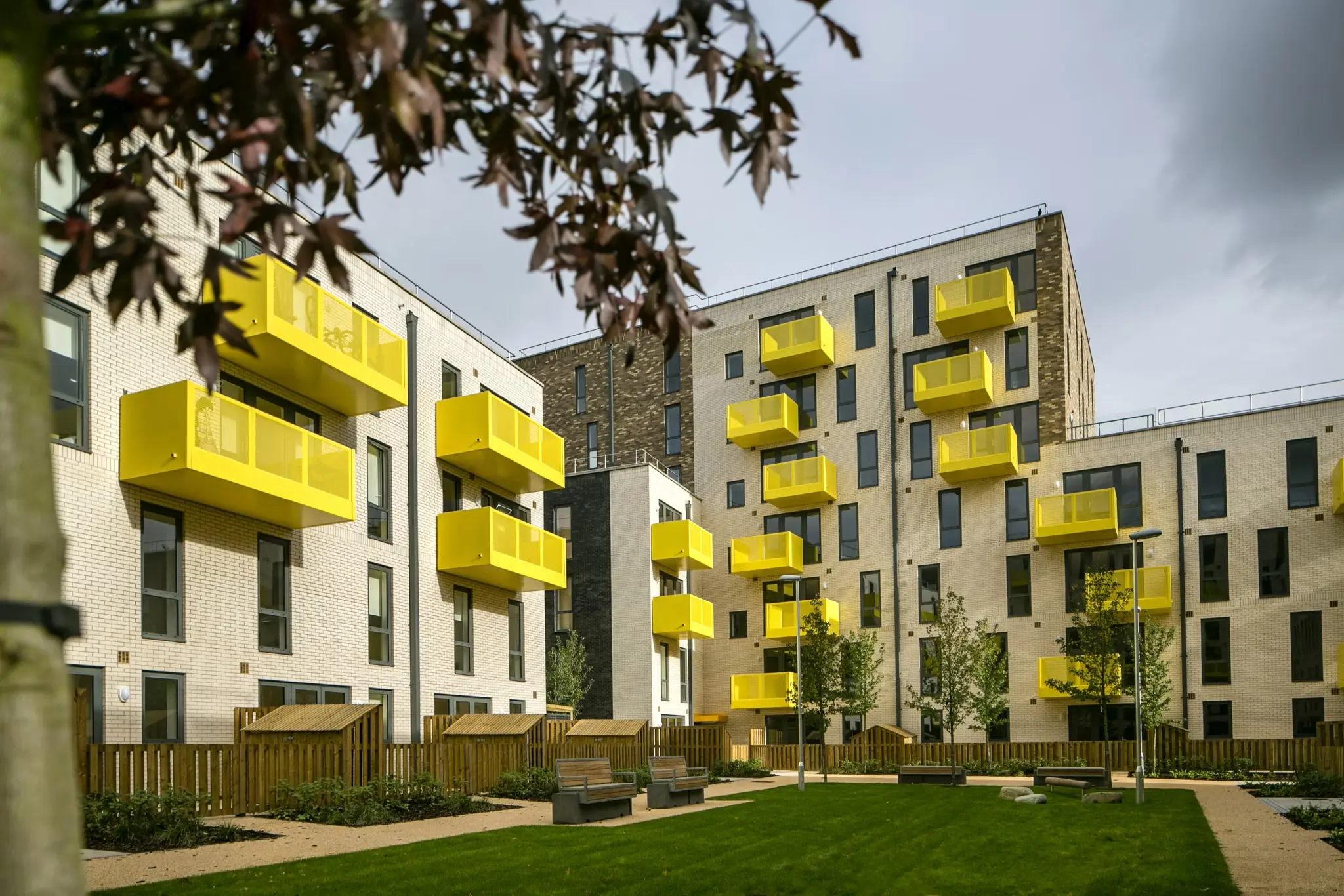 Fizzy Stepney Green exterior with modern brick facade, vibrant yellow balconies, and landscaped communal garden