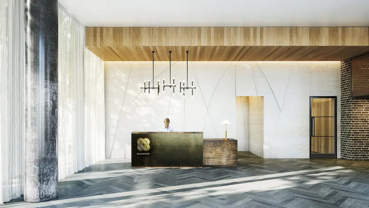 Thumbnail Bright and modern lobby at Sailmakers with wood and brass reception desk, chandelier lighting, and textured wall design