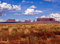 Landscape photograph of Monument Valley with blue sky and puffy clouds
