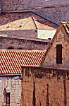 Color photograph of beige til roofs, stone buildings and geometric shapes