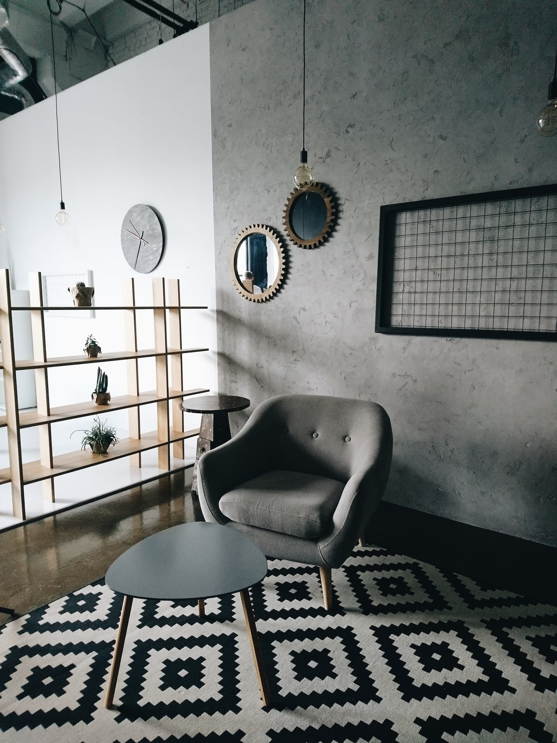 An office with a black and white rug and a gray armchair.