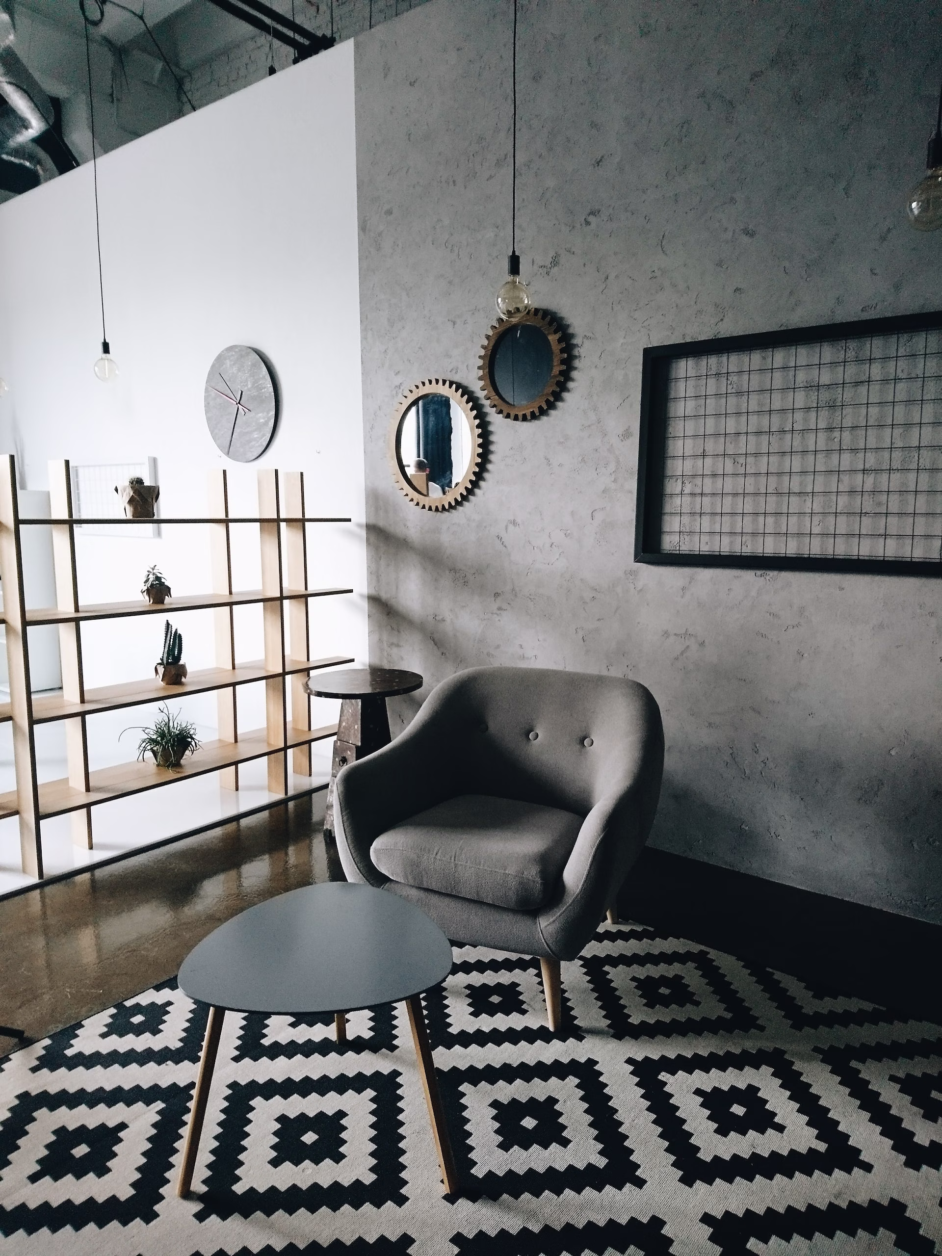 An office with a black and white rug and a gray armchair.