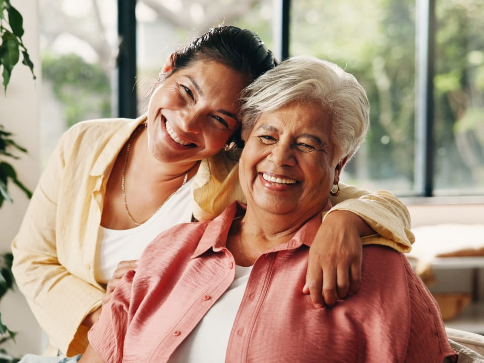 Adult daughter hugging her smiling mother at home