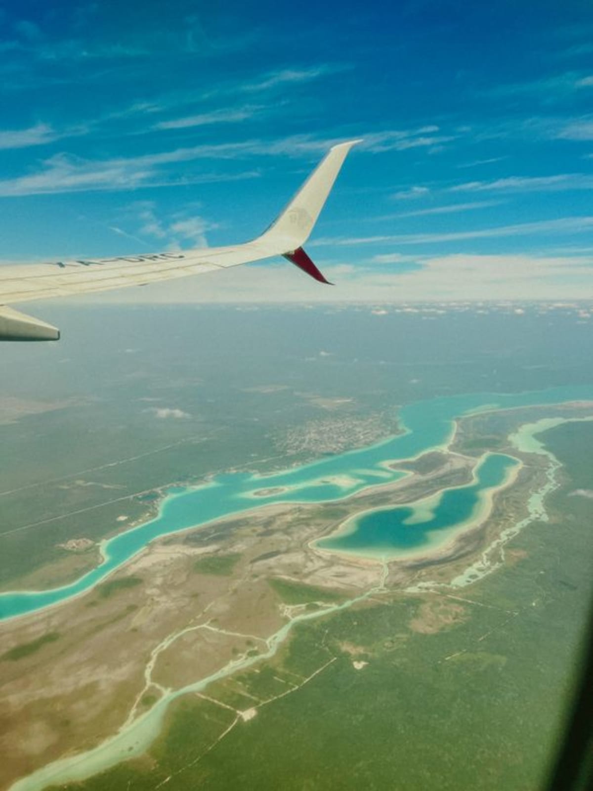Luftaufnahme aus einem Flugzeugfenster über der türkisfarbenen Lagune von Bacalar, Mexiko