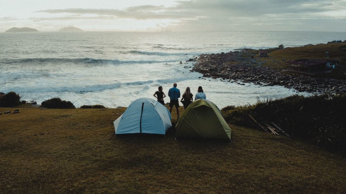 Group of campers relaxing on a tropical beach near the ocean at dusk