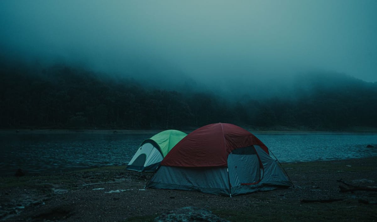 Tents pitched near calm tropical water at twilight for a camping trip in Mexico