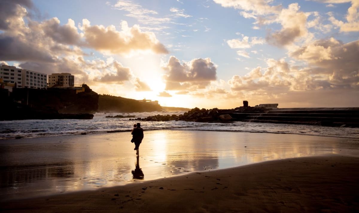 Parent carrying a child along the beach at sunset, an easy evening routine with a toddler