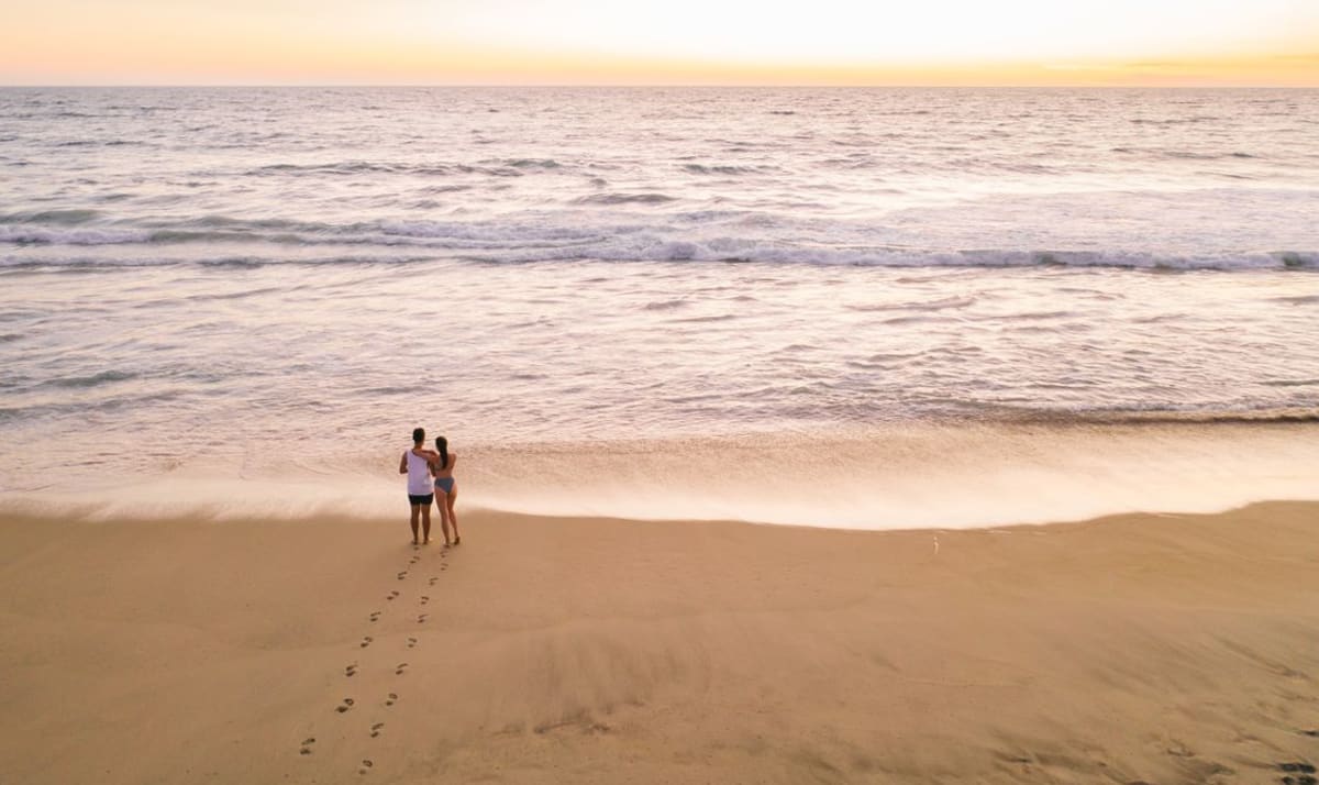 Couple walking along a sandy beach at sunset near Zicatela, a typical winter evening in Puerto Escondido