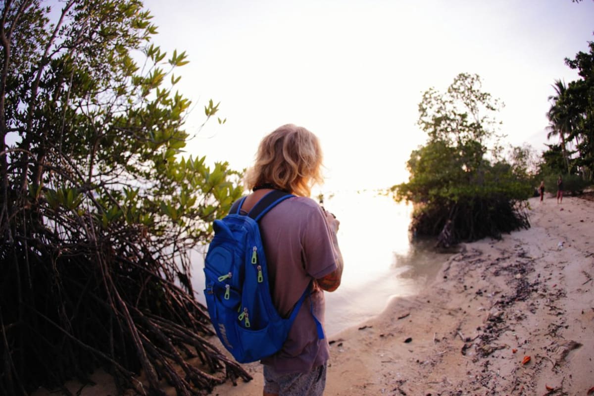 Solo backpacker walking along a tropical beach at sunset in Puerto Escondido Mexico