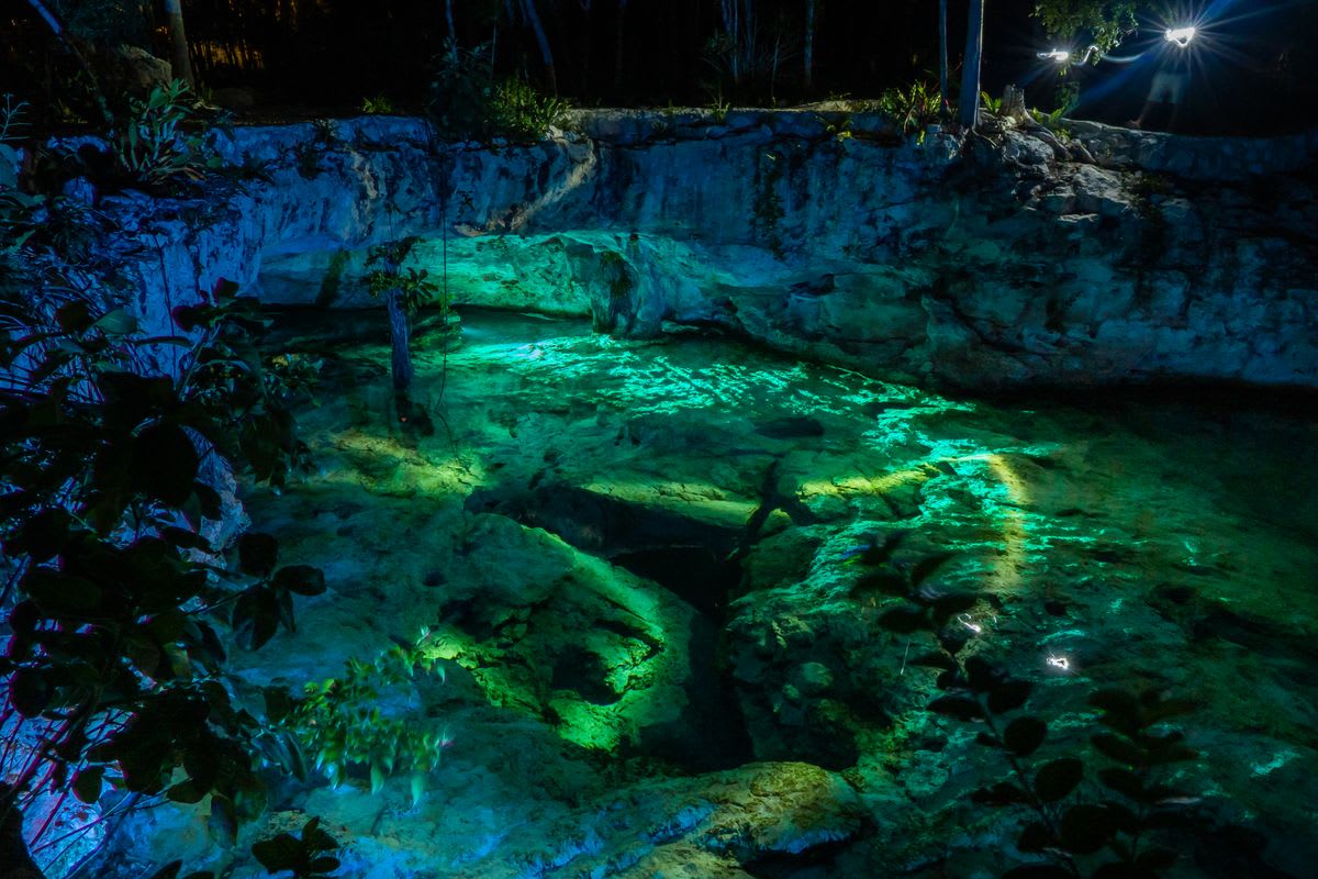 Vista nocturna del Gran Cenote en Tulum, México, con agua cristalina y stalactitas
