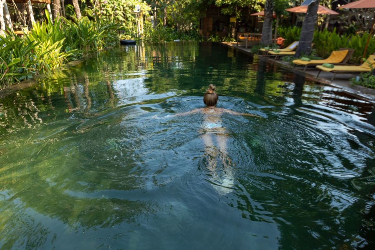 Woman swimming in a lush green tropical resort pool in Mexico