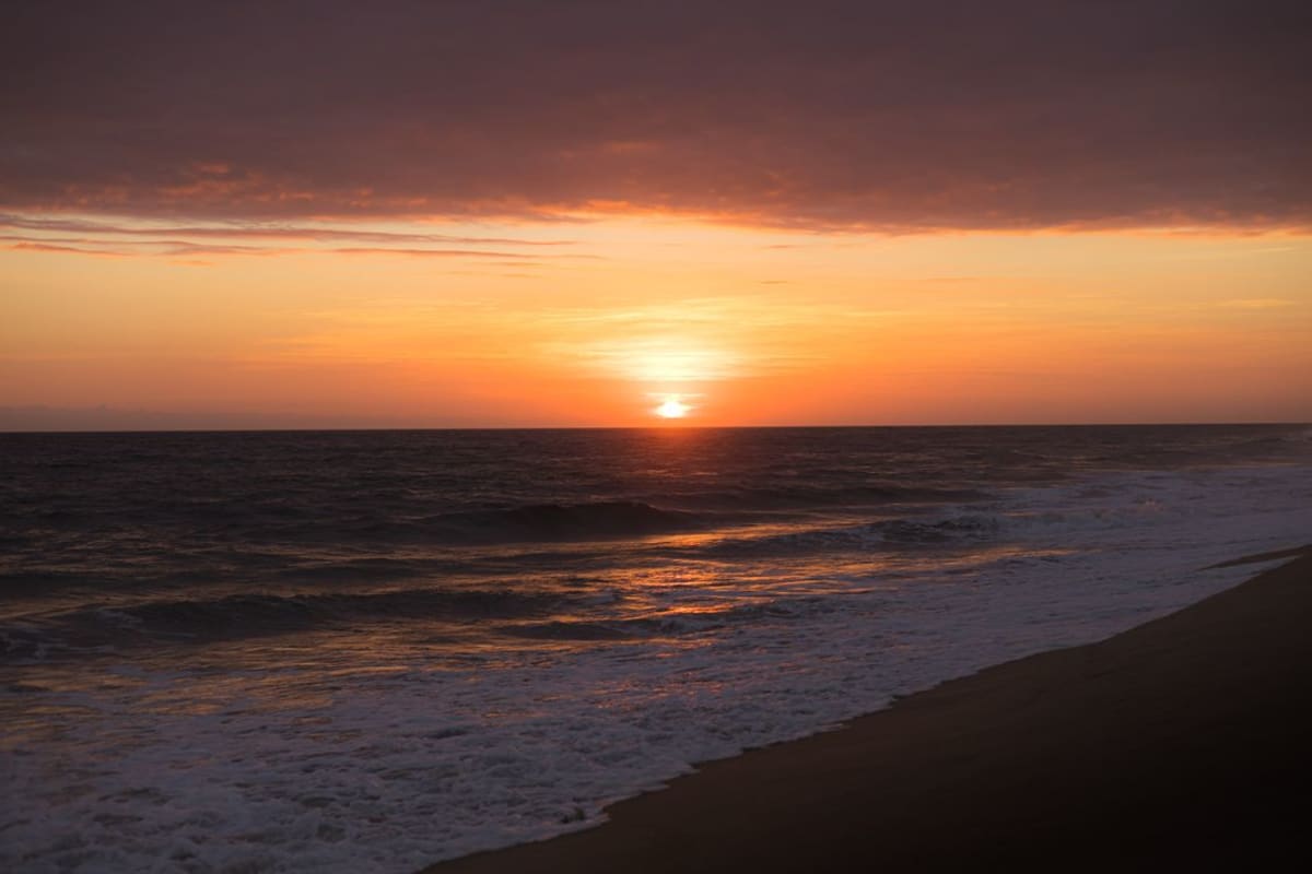 Küste von Puerto Escondido bei Sonnenuntergang mit dramatischem orangefarbenen Himmel über dem Pazifischen Ozean