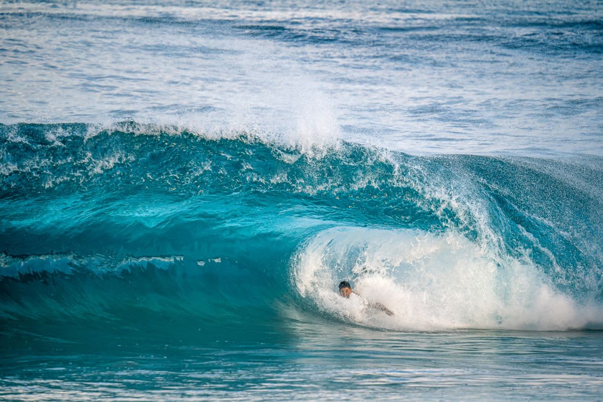 Surfer inside a powerful hollow barrel at a fast-breaking sand beach break