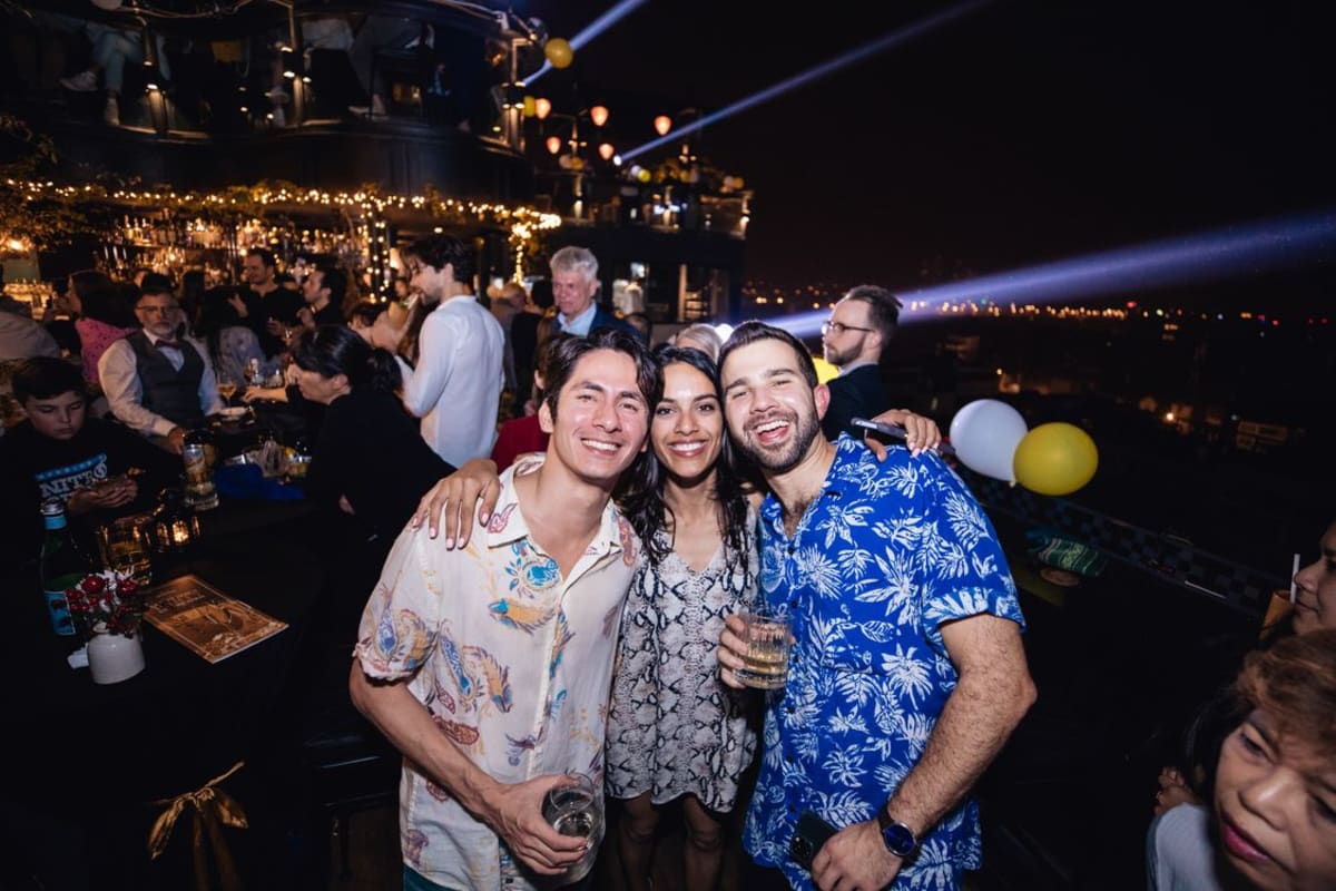 Friends enjoying drinks at a vibrant rooftop bar at night in a tropical destination