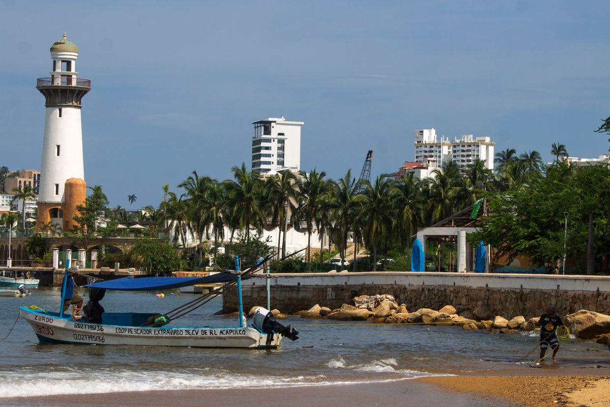 Acapulco lighthouse and traditional fishing boat in the port at sunset