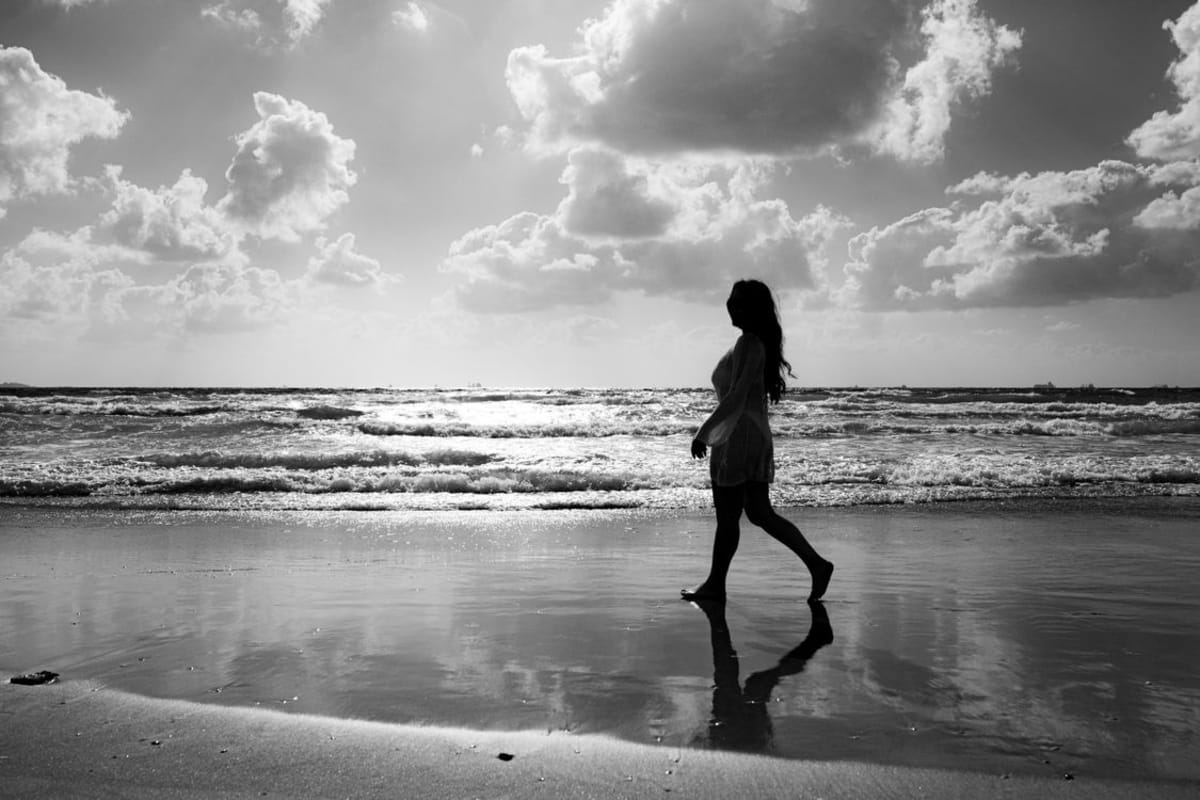 Alleinreisende Frau sitzt an einem tropischen Strand in Mexiko und blickt auf den Pazifischen Ozean