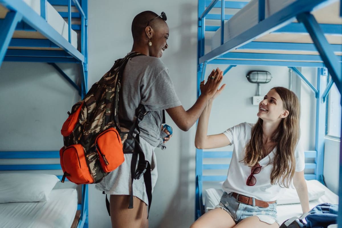 Solo backpackers celebrating in a bright hostel dorm room in Puerto Escondido Mexico