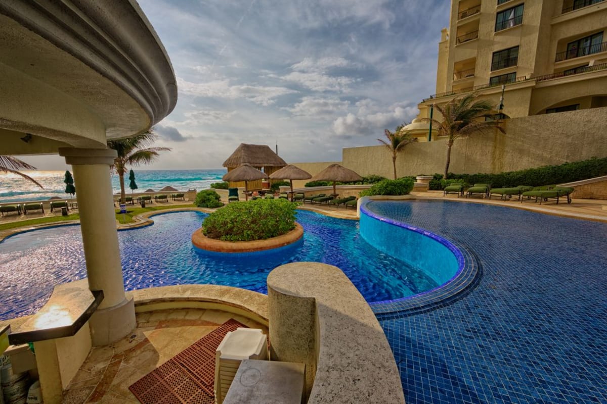 Luxury tropical resort pool with swim-up bar and lush greenery in Mexico