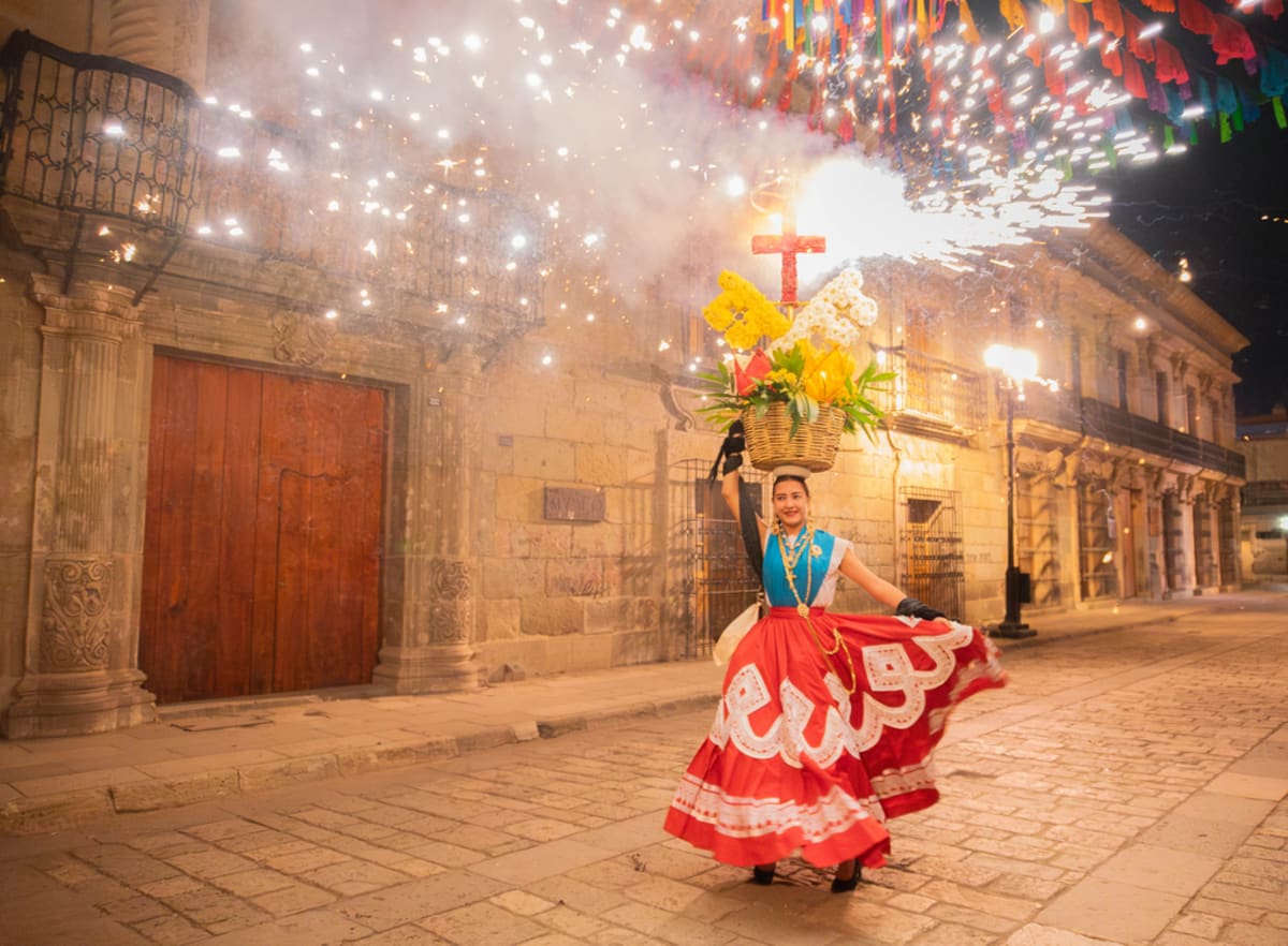 Frau in traditionellem oaxacanischem besticktem Kleid trägt einen Blumenkorb beim Guelaguetza-Kulturfestival in Oaxaca Mexiko
