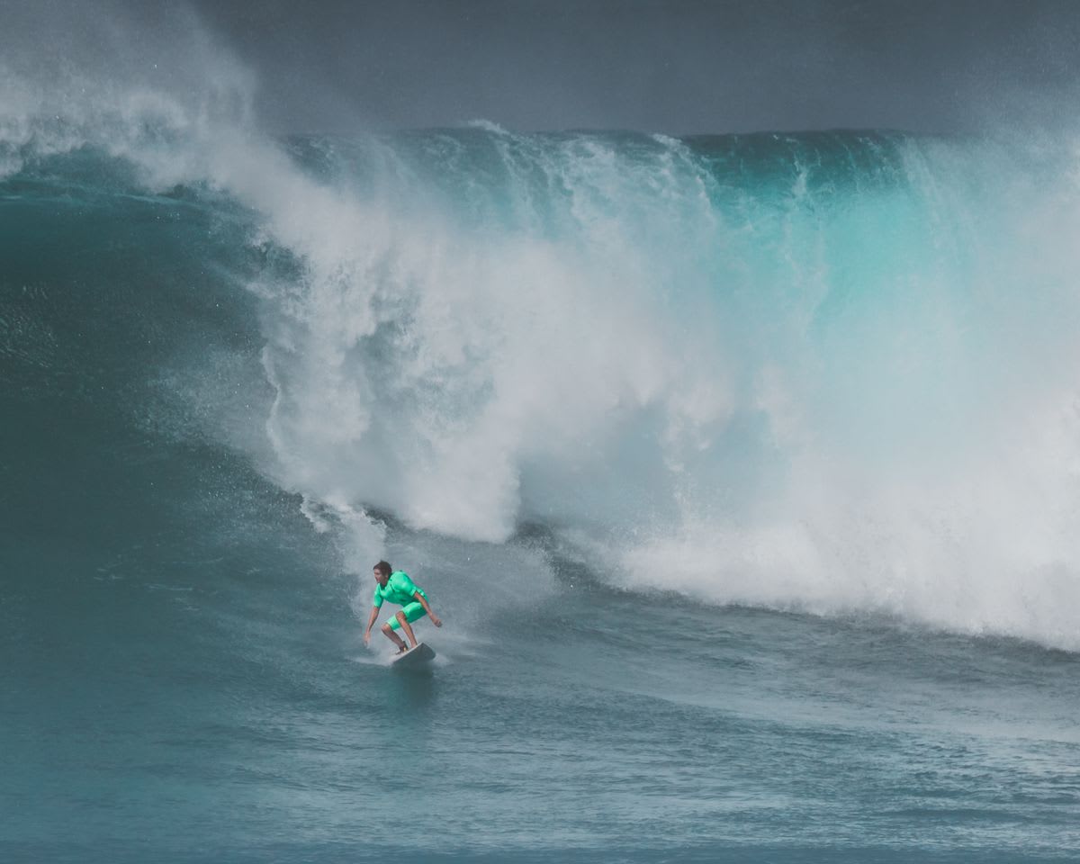 Surfista sobre una ola grande en el océano Pacífico bajo cielo azul