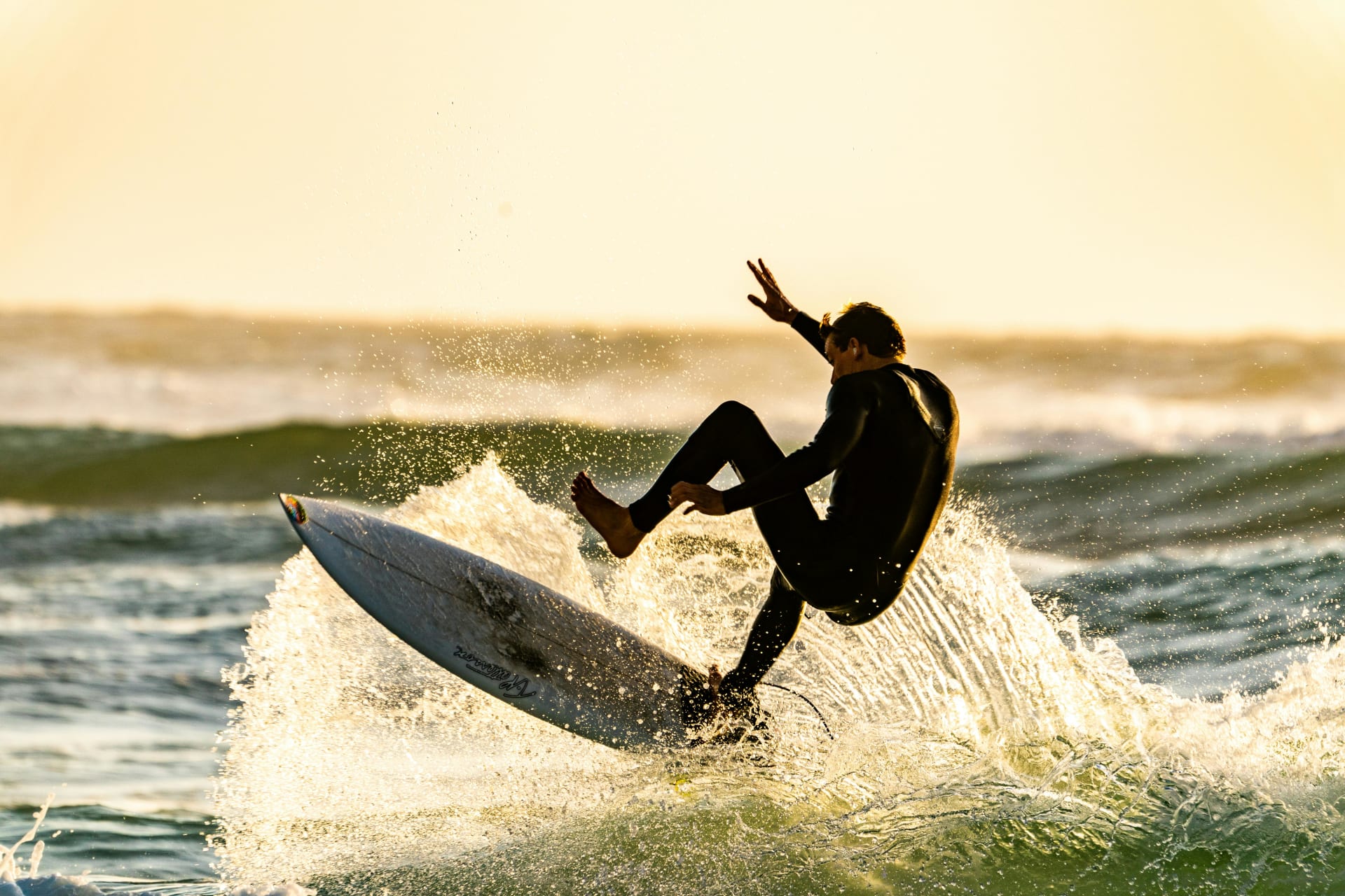 Surfer riding a powerful ocean wave at sunset