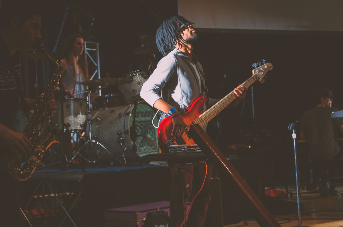 Live band performing on stage with guitars and drums at an energetic concert venue